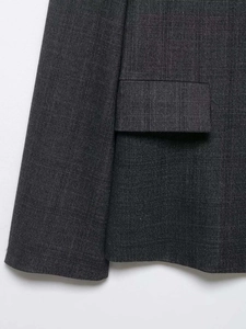 Detail of dark grey pinstripe blazer fabric and a flap pocket with fine stitching