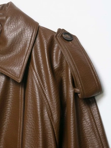 Detailed close-up of brown faux leather jacket texture with epaulettes and button accent