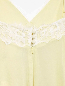 Close-up of light yellow dress featuring white lace trim, fabric buttons, and a hidden zipper