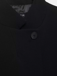 Detail of minimalist black blazer showing twill fabric texture and matching round button