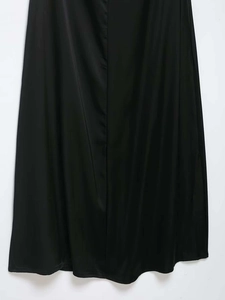 Détail du tissu en satin brillant et du drapé élégant de cette robe longue noire