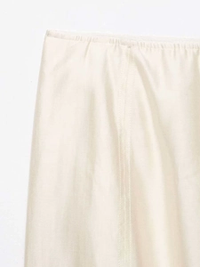 Détail de couture à la taille et texture satinée soyeuse sur la jupe midi crème