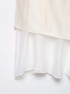 Détail d'une jupe midi beige à double épaisseur montrant la texture et la doublure en voile blanc