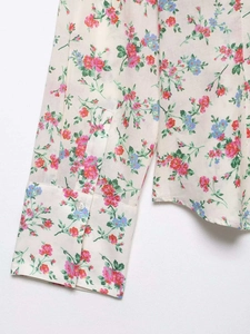 Detail of floral printed blouse sleeve with round button and precise stitching