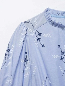 Close-up of floral print dress with ruffled stand collar and gathered shoulder detail