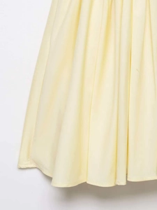 Détail d'une robe trapèze jaune clair avec tissu micro-plissé et finition d'ourlet soignée