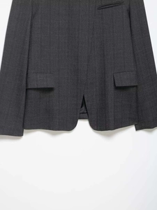 Detail view of dark grey striped blazer showing flap pockets and back hem vent