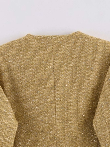 Close-up of golden tweed fabric with woven metallic threads and subtle sequins detail