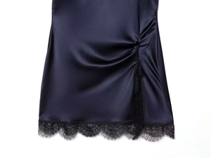 Close-up of midnight blue satin dress hem featuring black eyelash lace trim and ruched detail