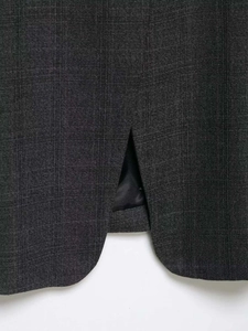 Detail of dark grey plaid blazer hem featuring precise back slit and smooth black lining