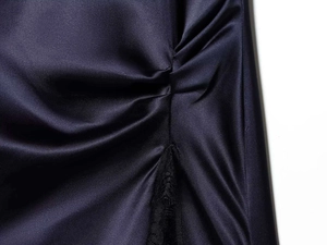Detail view of navy satin mini dress featuring side ruching and delicate black lace trim