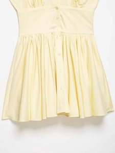 Détail de la robe sans manches jaune clair avec boutons et taille plissée élégante
