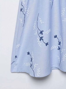 Detail of light blue dress with intricate navy and white floral embroidery