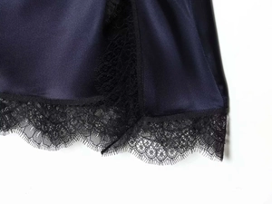Detailed macro view showing navy blue satin fabric with delicate black eyelash lace trim