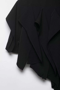 Détail d'une jupe noire avec des volants géométriques irréguliers et coutures fines