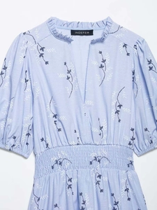 Detailed close-up of light blue floral embroidery on v-neck dress with elastic waist
