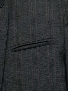 Close-up of grey pinstripe suit jacket featuring a welt pocket and matte black button