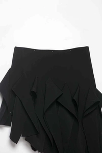 Détail de l'ourlet irrégulier à volants et des coutures sur une mini-jupe noire