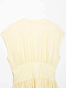 Détail de la robe sans manches jaune clair avec plis verticaux et taille haute