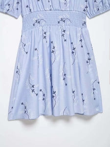 Detail view of smocked elastic waist and blue floral embroidery on light blue dress