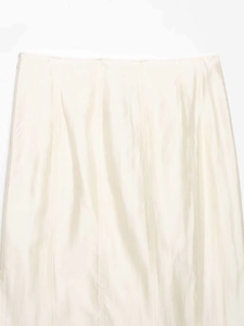 Gros plan d'une jupe midi crème montrant la texture satinée et les détails de couture