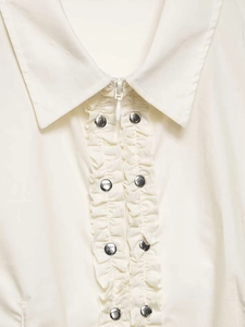 Close-up of cream poplin shirt featuring ruffled trim and silver rivet button detailing