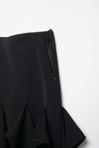 Détail d'une jupe noire avec fermeture éclair invisible et texture plissée à volants