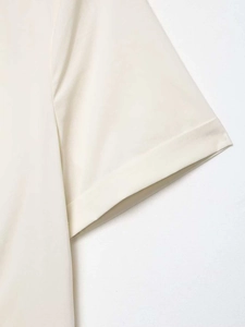 Close-up detail of cream poplin shirt sleeve showing clean stitching and refined cotton fabric