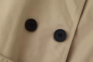 Macro shot of matte black double-breasted buttons and twill fabric texture on a khaki coat