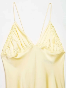 Détail du décolleté en V plissé et du tissu satiné sur une robe mi-longue jaune beurre doux