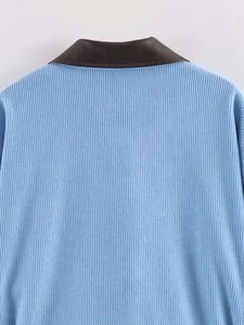 Macro detail of sky blue ribbed knit jacket with contrasting brown faux leather collar