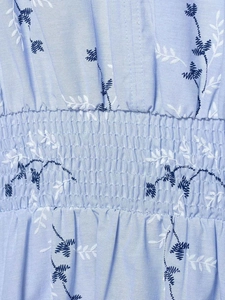 Close-up of smocking detail on light blue dress with navy floral embroidery pattern