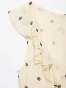 Vue détaillée du tissu en mousseline à pois crème avec bords à volants élégants et texture