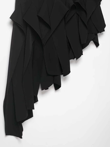 Détail de l'ourlet à volants irréguliers multicouches sur une jupe en tissu noir