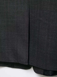 Close-up of charcoal grey textured mixed-fabric blazer showing hem and lining detail