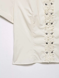Detail view of cream poplin shirt with silver metallic studs and ruffled decorative trims