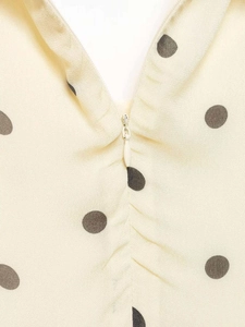 Détail de la fermeture éclair invisible et du motif à pois noirs sur tissu crème