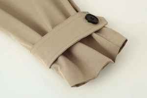 Detailed macro view of khaki trench coat cuff with adjustable strap and black button