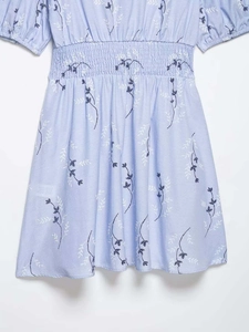 Detail of smocked waist on light blue floral dress with white leaf print and soft fabric