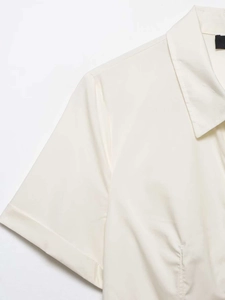 Detail of shoulder seams and lapel collar on a white poplin shirt with rivet accents