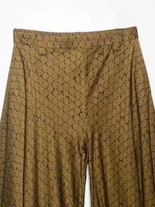 Detail shot of snakeskin pattern and belt loops on yellow wide-leg trousers fabric