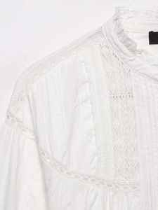 Detail of white blouse featuring high collar lace patchwork and delicate vertical pleats
