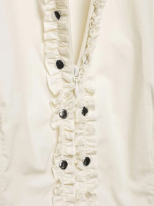 Detail of ivory poplin shirt with centered zipper, ruffles, and silver metal studs