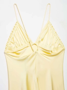 Détail d'une robe midi en satin jaune clair avec volants délicats et fines bretelles