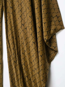 Detail shot of shimmering bronze fabric featuring a black snake skin geometric pattern