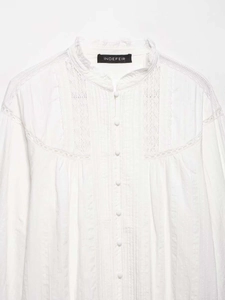 Detail of white shirt featuring a ruffled stand-up collar and delicate lace embroidery