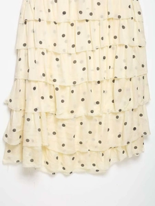 Détails des volants superposés sur une robe crème à pois noirs en tissu léger fluide
