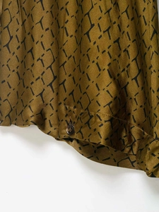 Close-up of geometric pattern fabric with resin button on brown wide leg pants