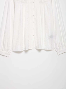 Detail of white long sleeve shirt with vertical texture, lace splicing and fabric buttons
