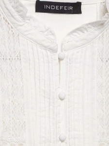 Detail of white lace top showing V-neckline with ruffles and neat pleats on cotton fabric